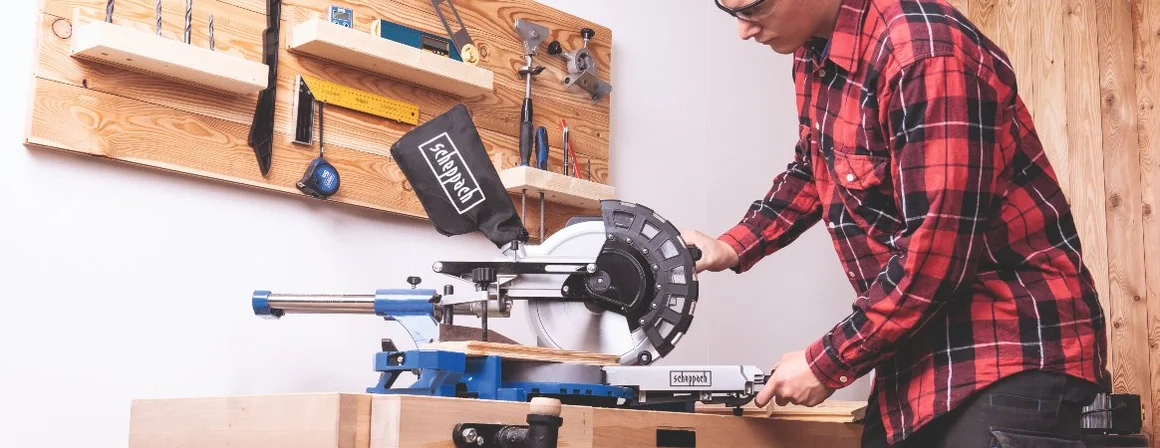 Person benutzt Kappsäge auf Werkbank